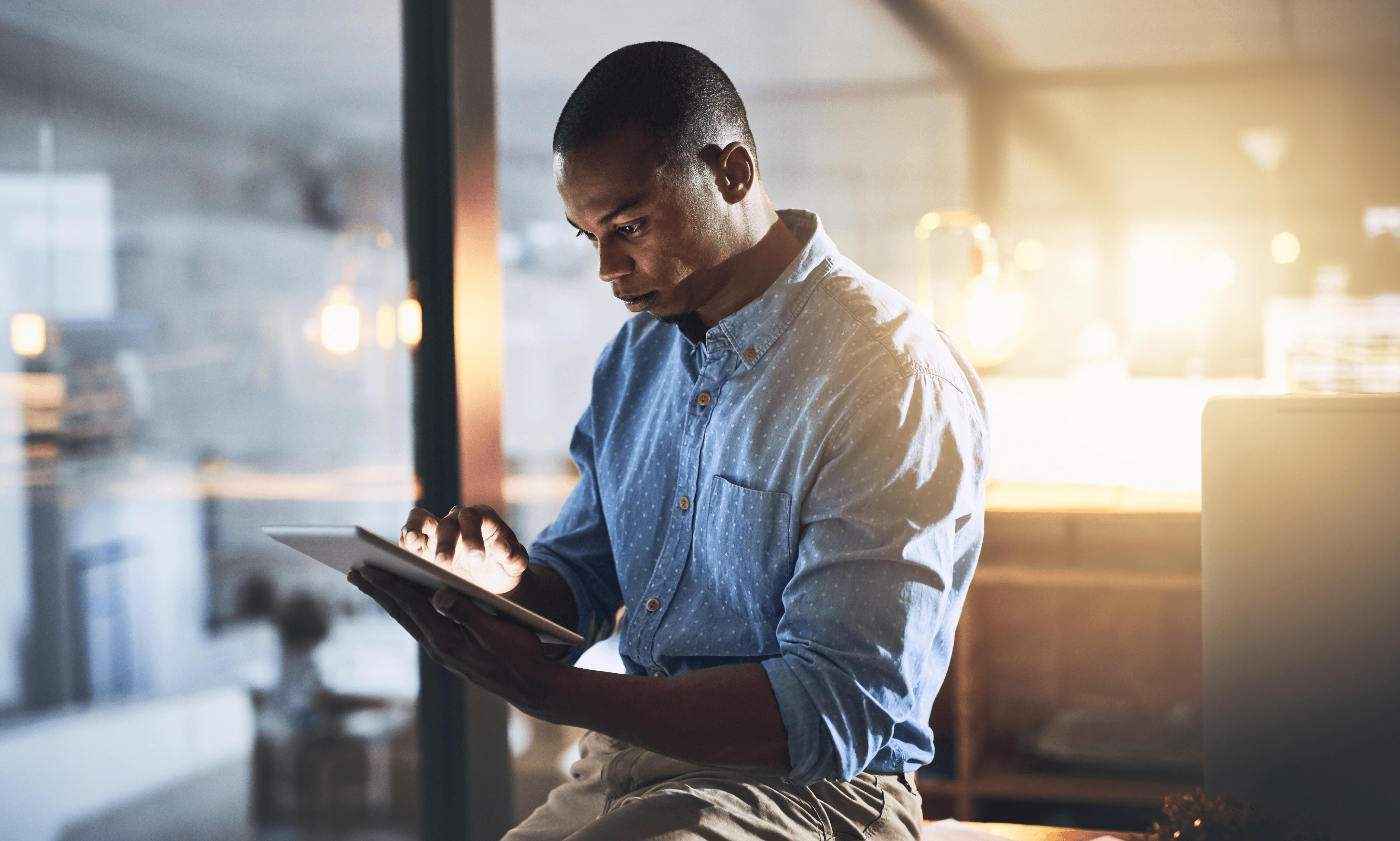 Person looking at mobile device while leaning on desk.